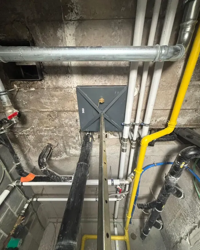Colonne de carottage étayée contre le plafond, entre les conduites d’un local technique.
