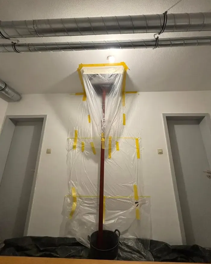 Zone de carottage confinée sous film plastique, du plafond jusqu’au seau.