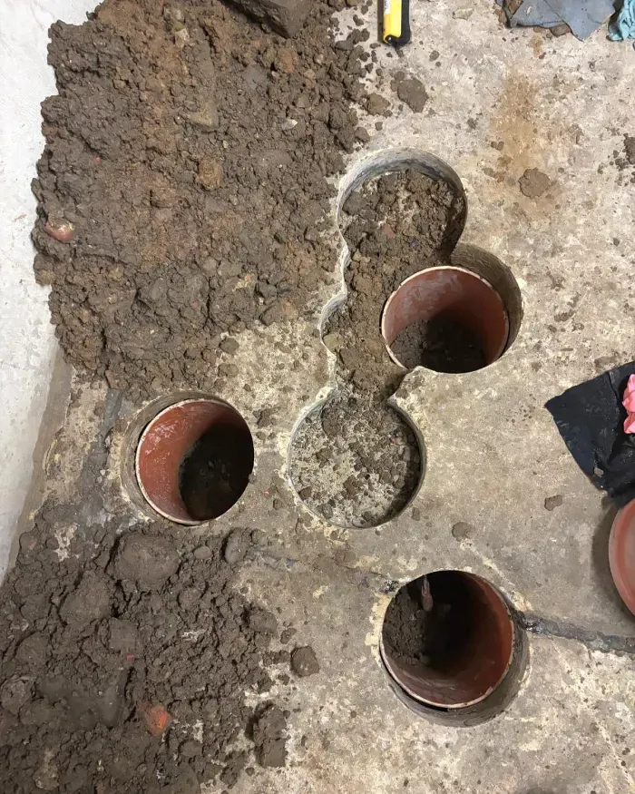 Plusieurs carottages dans la dalle, la terre dégagée en dessous.