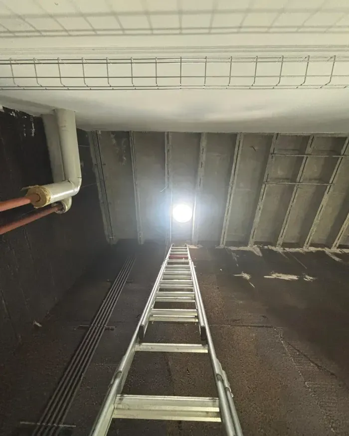 Échelle dressée vers le plafond, que le carottage traverse jusqu’au jour.
