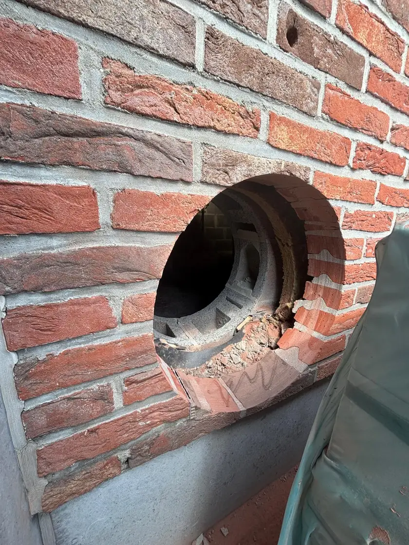 Carottage de grand diamètre dans un mur creux : la coupe laisse voir la brique de parement, l’isolant et le bloc intérieur.